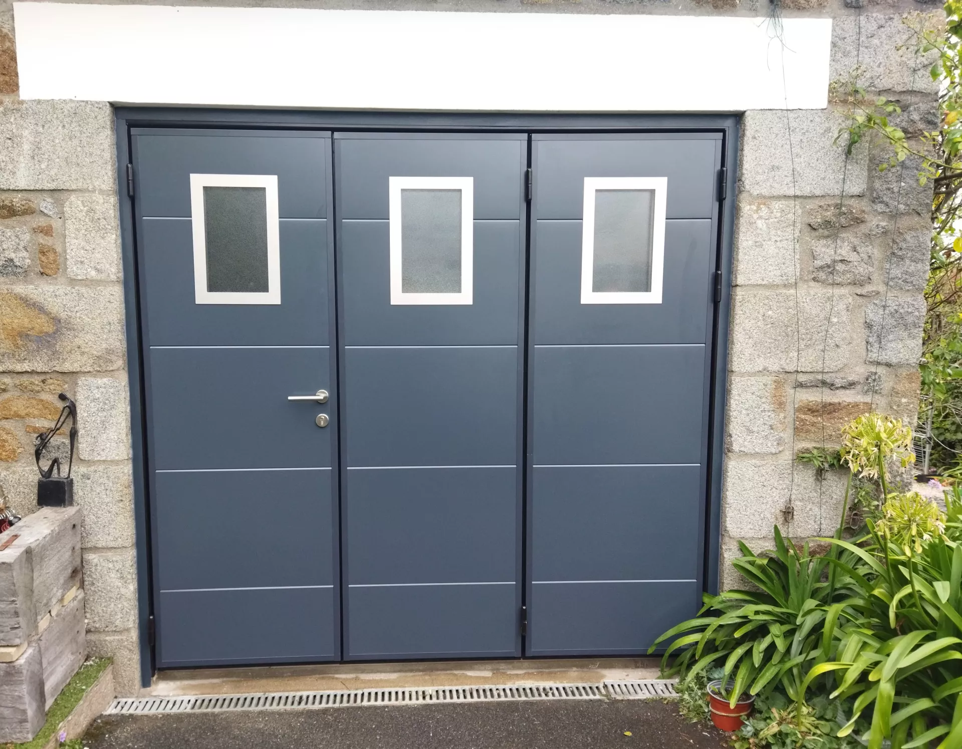 Porte de garage MOOS 3 battants avec ouvertures à gauche vers l'extérieur et hublots alunox